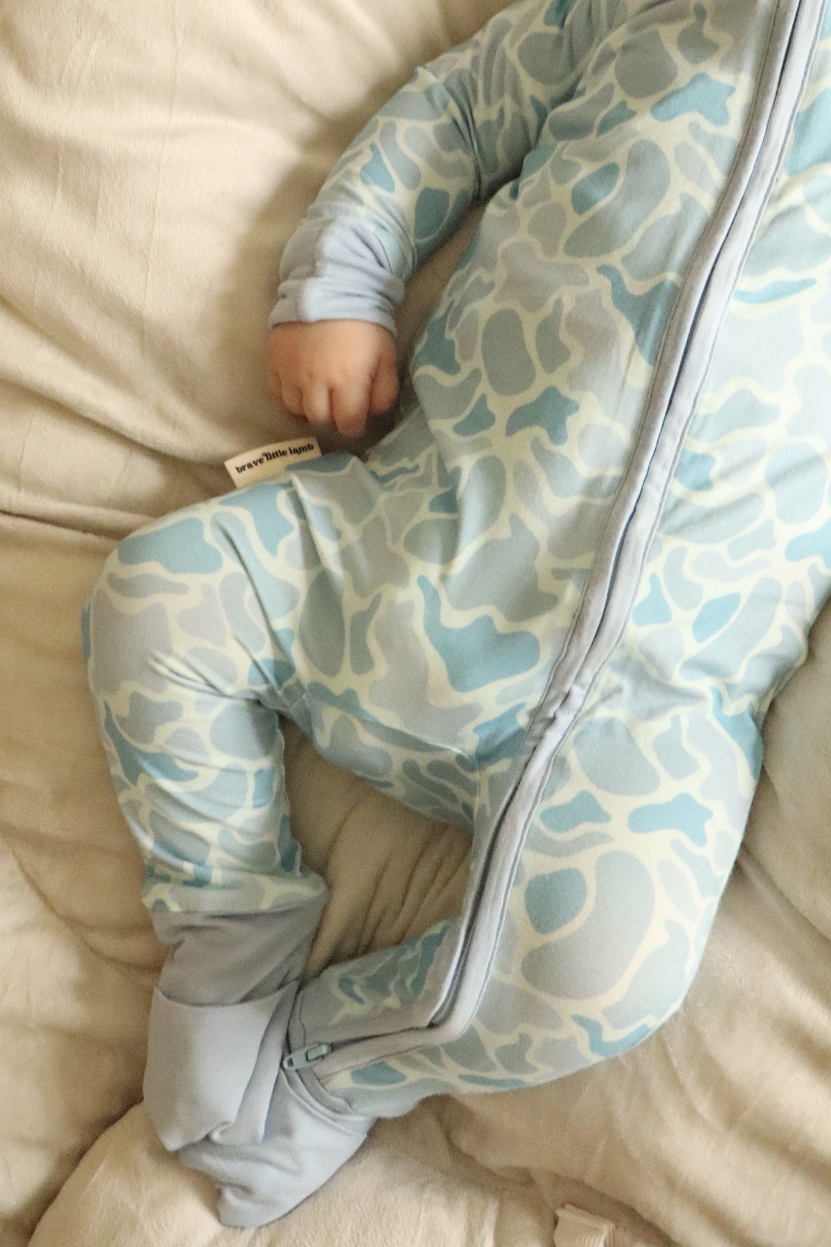 Child wearing a patterned onesie on a beige couch