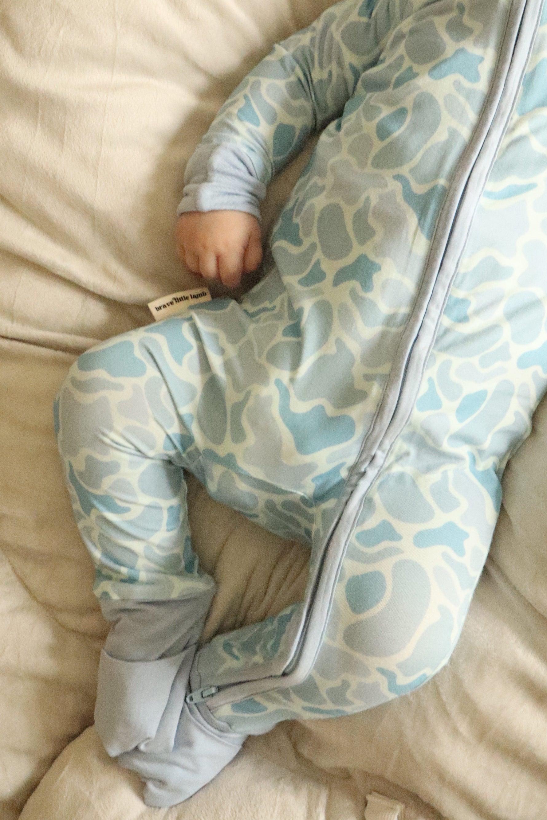 Child wearing a patterned onesie on a beige couch