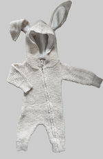 Knitted baby romper with bunny ears on a gray surface