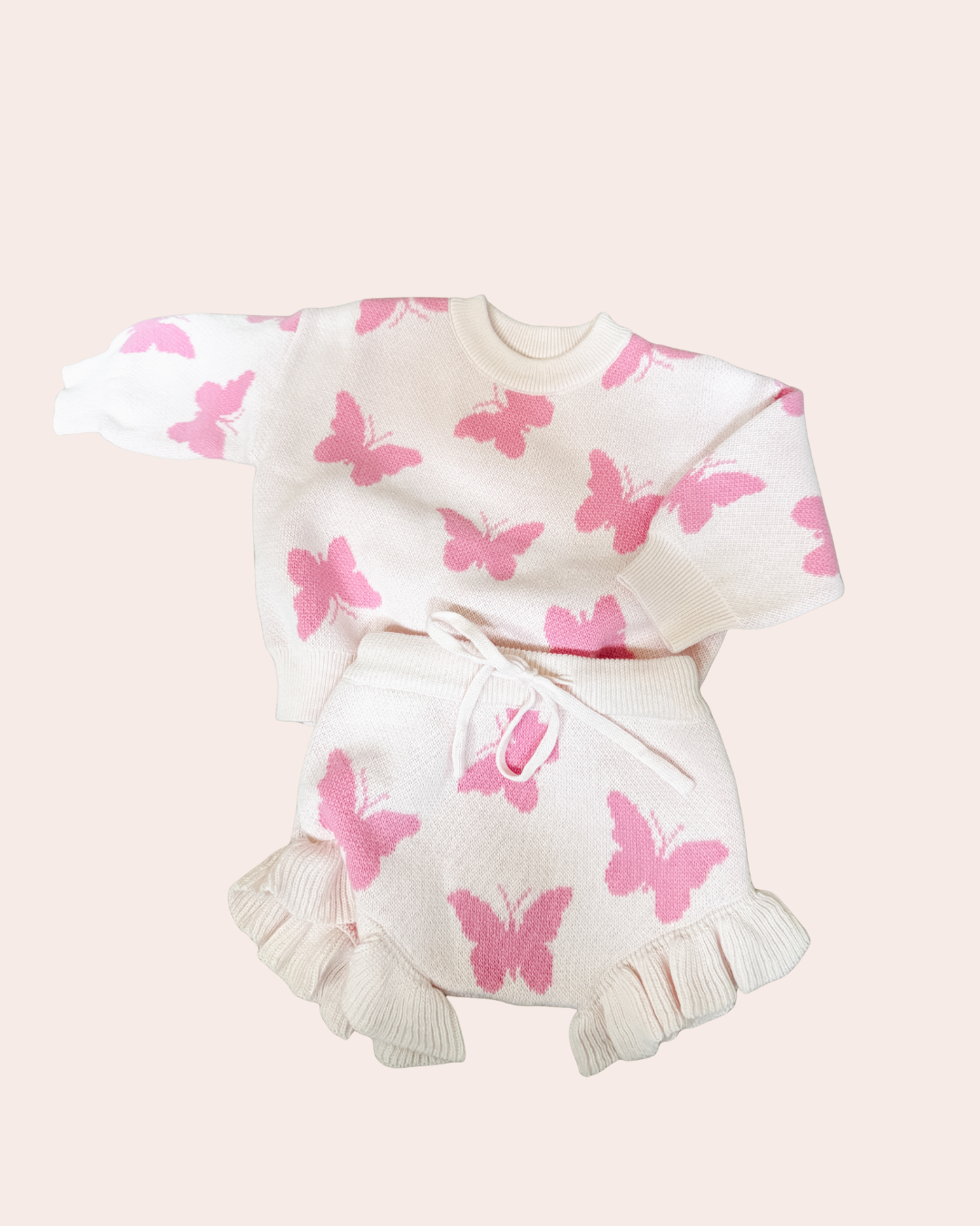 White outfit with pink butterfly patterns on a light pink background