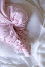 Pink baby outfit with ruffles on a white background