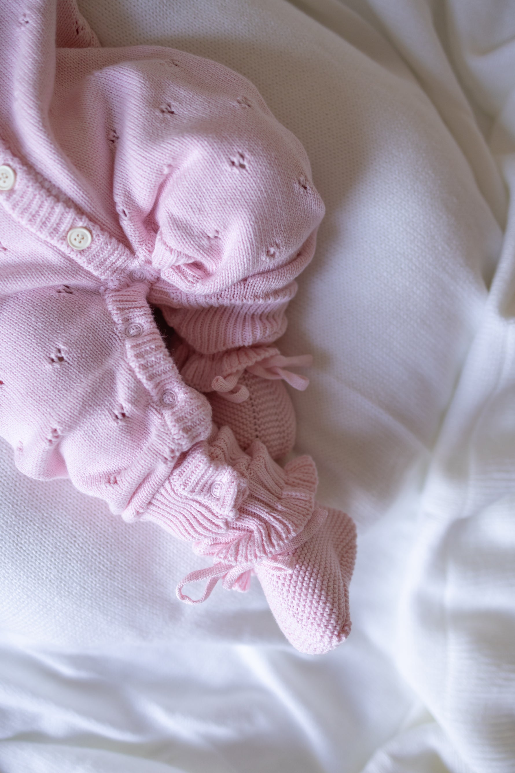 Pink baby outfit with ruffles on a white background