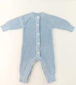 Blue knitted baby romper on a light beige background