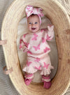 Baby in a pink butterfly outfit with a large bow in a woven basket