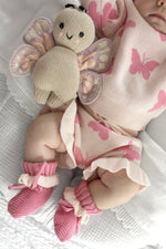 Baby doll wearing pink butterfly-patterned outfit with a plush butterfly toy.