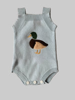 Knitted baby romper with duck design on a beige background
